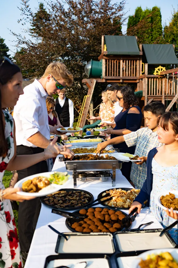 Guests serving themselves from a buffet line at an outdoor reception