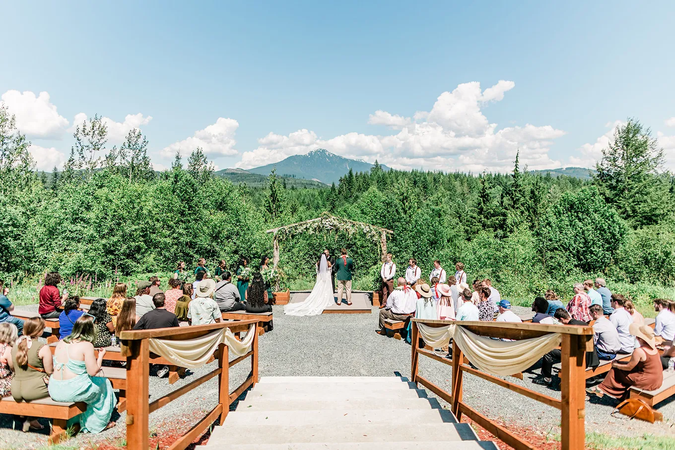 Outdoor mountain-view wedding ceremony beneath a floral arch