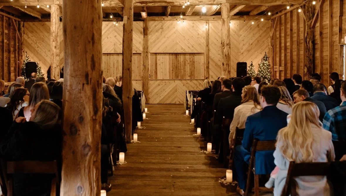 Candlelit wedding ceremony aisle inside a timber-frame barn