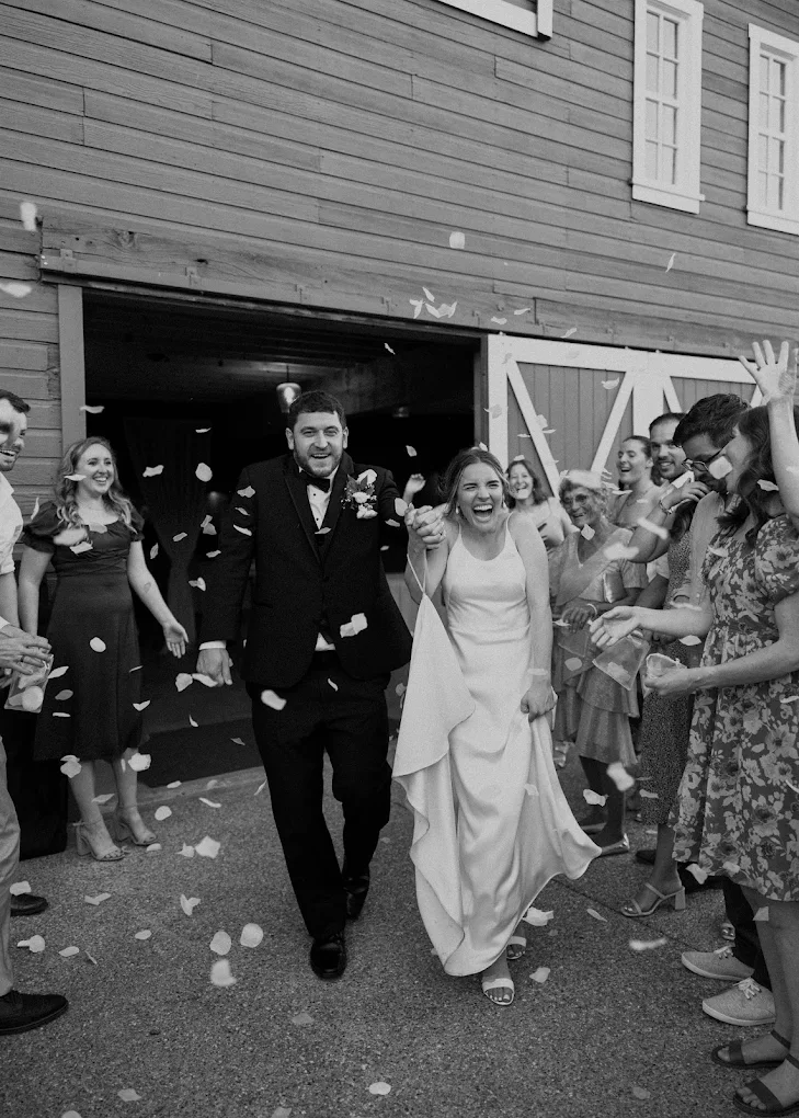 Black-and-white photo of newlyweds walking through a confetti send-off