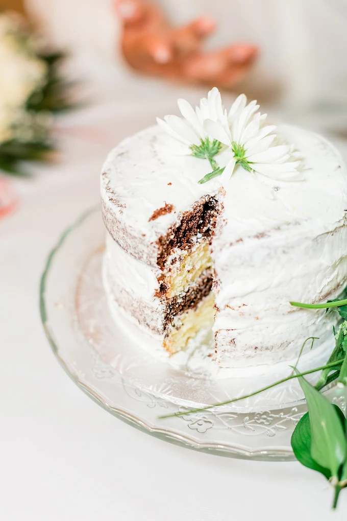 Sliced naked wedding cake garnished with a fresh daisy