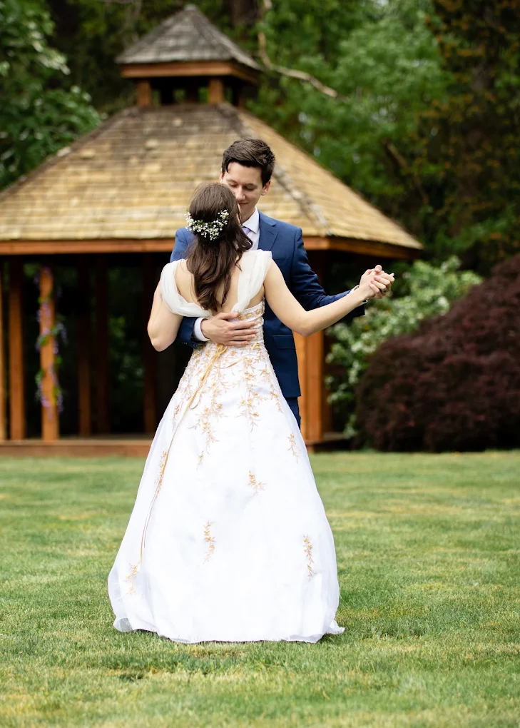 Bride and groom dancing on the lawn in front of a wooden gazebo