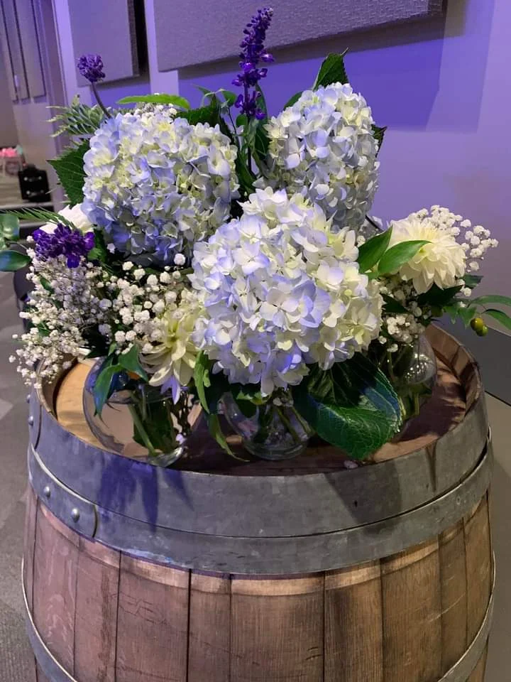 Blue and white hydrangea floral centerpiece displayed on a wine barrel