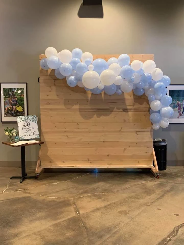 Wood-paneled photo backdrop decorated with a blue and white balloon garland